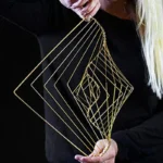 Intricate geometric wire art sculpture held by a person, showcasing modern abstract design with gold-colored metal wires.