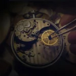 A close-up of a watchmaker's hand using tweezers to adjust the gears inside a mechanical watch. The image highlights the detailed craftsmanship involved in watch repair and assembly.