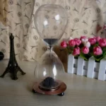 Modern glass hourglass with black sand flowing between chambers, perfect for educational demonstrations and stylish decor.