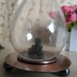 Decorative magnetic lava lamp with black lava inside a glass globe, mounted on a wooden base with metal accents, ideal for science decor and educational displays.