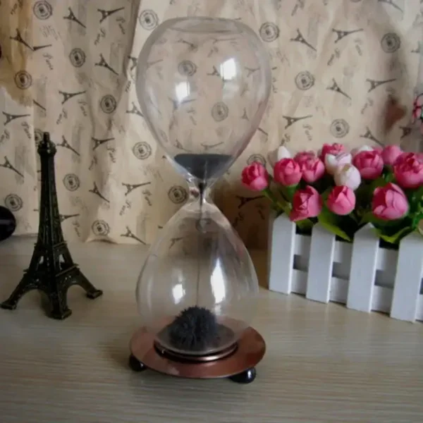 Elegant sand timer with black sand flowing through glass, set on a copper-colored base, ideal for educational and decorative purposes.
