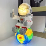 An astronaut LEGO figure holding a glowing moon, standing on a colorful Earth-inspired base. The scene combines science and creativity, perfect for educational and decorative purposes.