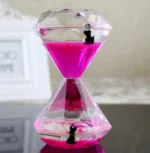 Clear acrylic hourglass sand timer with pink sand and small penguin figurines inside, perfect for science decor and educational demonstrations.