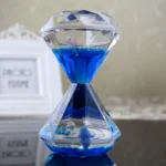 Elegant crystal hourglass with blue liquid and floating objects, perfect for science decor and educational purposes.