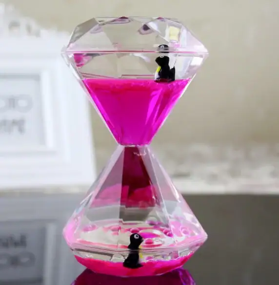 Clear acrylic hourglass sand timer with pink sand and small penguin figurines inside, perfect for science decor and educational demonstrations.