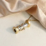 Elegant gold-tone telescope pendant necklace with a delicate chain, designed as a miniature telescope for fashion and educational purposes.