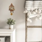 Elegant wooden cuckoo clock with intricate details and a tassel wall hanging. Perfect for adding a vintage touch to home decor and creating a cozy, timeless atmosphere.