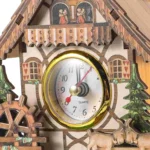 Traditional wooden cuckoo clock featuring a chalet-style house with detailed carvings, miniature trees, and small figurines on the roof, showcasing classic craftsmanship.