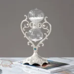 Elegant glass hourglass with intricate metal stand for science decor or educational purposes.