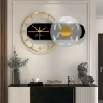 Stylish modern wall clock with gold accents, black and white decorative elements, and artistic sculptures on a sleek black and white console table in a contemporary interior.