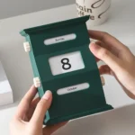 A green desktop flip calendar displaying the date October 8, Sunday, with a hand adjusting the date.