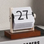 Vintage flip clock calendar with wooden base displaying the number 27, showcasing a retro design for educational or decorative use.