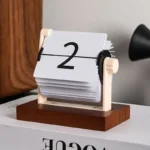 Vintage-style flip calendar clock showing the number 2, used as an educational desk accessory for teaching numbers and time concepts.