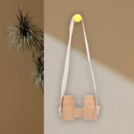 Brightly colored wooden binoculars toy hanging on a wall with a yellow magnet, designed for children to explore and learn about nature and birds.