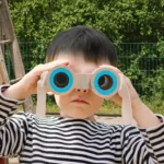 Child playing with DIY binoculars toy outdoors.