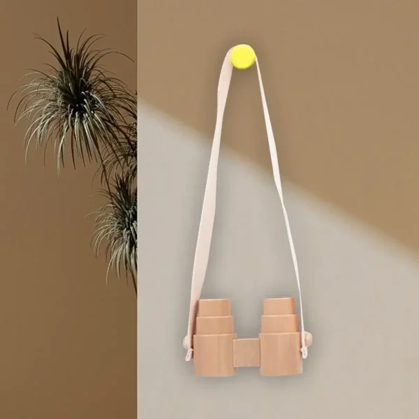 Brightly colored wooden binoculars toy hanging on a wall with a yellow magnet, designed for children to explore and learn about nature and birds.