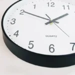Elegant black and white quartz wall clock showing time with clear numerals and hands.
