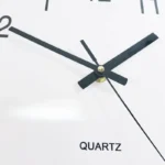 Close-up of a modern quartz wall clock with black hands and minimalistic design, suitable for science-themed decor and educational settings.