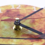 Close-up of a vintage-style wall clock with a leaf pattern face, black hour and minute hands, and a gold second hand, perfect for science-themed decor and educational settings.