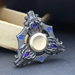 Metal fidget spinner featuring an intricate dragon design with blue gemstone accents, designed for stress relief and focus.