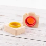 Colorful wooden camera with a red lens and yellow ring, designed for children’s play and learning.