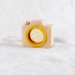 A wooden camera toy with a yellow lens and a textured mirror, designed for children to explore and learn through play.