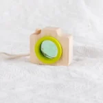 Wooden camera toy with a green lens, designed for children’s educational activities and science exploration. Perfect for encouraging creativity and curiosity in young learners.
