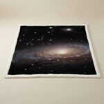 A cozy blanket featuring a detailed print of a galaxy with stars and cosmic clouds, perfect for science enthusiasts and space lovers.