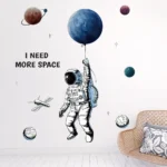 Astronaut wall decal with planets and stars, featuring the phrase "I NEED MORE SPACE" for a space-inspired room decor.