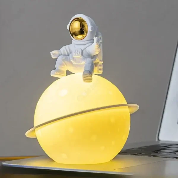 Bright yellow planet lamp with a small astronaut figurine sitting on top, creating a playful and educational decor piece.