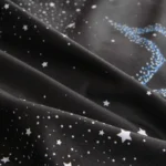 Black fabric with white star patterns and blue glitter accents, ideal for science-themed decor and educational projects.