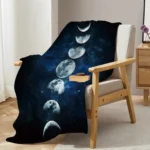 Cozy space-themed throw blanket featuring moon phases draped over a modern armchair in a stylish living room. Perfect for astronomy enthusiasts and adding a celestial touch to home decor.