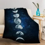 Cozy galaxy-themed throw blanket featuring moon phases design draped over a white sofa in a modern living room.