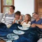 A family enjoying a cozy movie night on the sofa with a galaxy-themed blanket featuring moon phases, surrounded by popcorn and snacks, creating a fun and educational space-themed atmosphere.