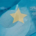 Bright yellow star-shaped balloon floating against a clear blue sky.