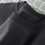 Black crewneck sweatshirt with ribbed collar, close-up view.