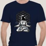 Comfortable navy T-shirt featuring a detailed astronaut illustration sitting in a meditative pose with a geometric background, perfect for science and space enthusiasts.