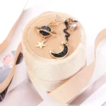 Elegant celestial-themed earrings featuring a moon, star, and planet design with black and gold accents, perfect for adding a cosmic touch to your jewelry collection.