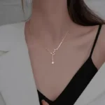 Close-up of a delicate gold necklace featuring a star-shaped pendant, worn by a woman with a black top and white blazer, highlighting stylish jewelry for women.