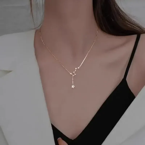 Close-up of a delicate gold necklace featuring a star-shaped pendant, worn by a woman with a black top and white blazer, highlighting stylish jewelry for women.