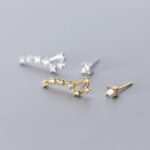 Close-up of gold and silver earrings featuring sparkling stones on a neutral background.