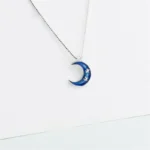 A celestial-themed necklace featuring a blue crescent moon with embedded stars, perfect for science lovers and astronomy enthusiasts.