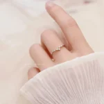 A close-up of a delicate constellation-inspired ring with small sparkling stones on a person's finger.