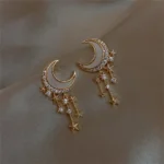 Elegant moon and star-themed dangle earrings with sparkling crystals and gold-tone finish. Perfect for adding a touch of cosmic charm to any outfit.