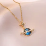 Elegant gold necklace featuring a blue planet pendant displayed in a luxurious wooden jewelry box, perfect for gift-giving or personal collection.