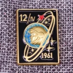 Gold and black space exploration badge featuring an astronaut helmet, planetary rings, stars, and the year 1961.