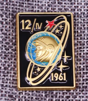 Gold and black space exploration badge featuring an astronaut helmet, planetary rings, stars, and the year 1961.