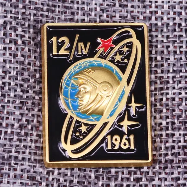 Gold and black space exploration badge featuring an astronaut helmet, planetary rings, stars, and the year 1961.
