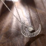 Elegant silver moon pendant necklace featuring detailed filigree patterns, hanging on a delicate chain against a rustic wooden background. Perfect for astrology lovers and stylish accessories.