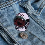 Vintage Soviet bear enamel pin wearing a space helmet with "CCCP" inscription, attached to denim fabric. Perfect for space enthusiasts and collectors of retro space memorabilia.